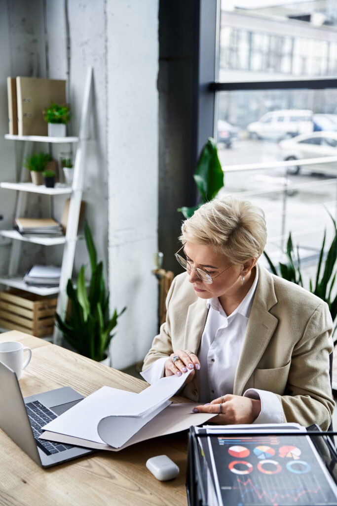 a fashionable woman reviews documents at her sleek workspace filled with plants.